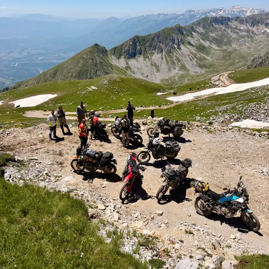 Six riders and loaded bikes at a high gravel pass