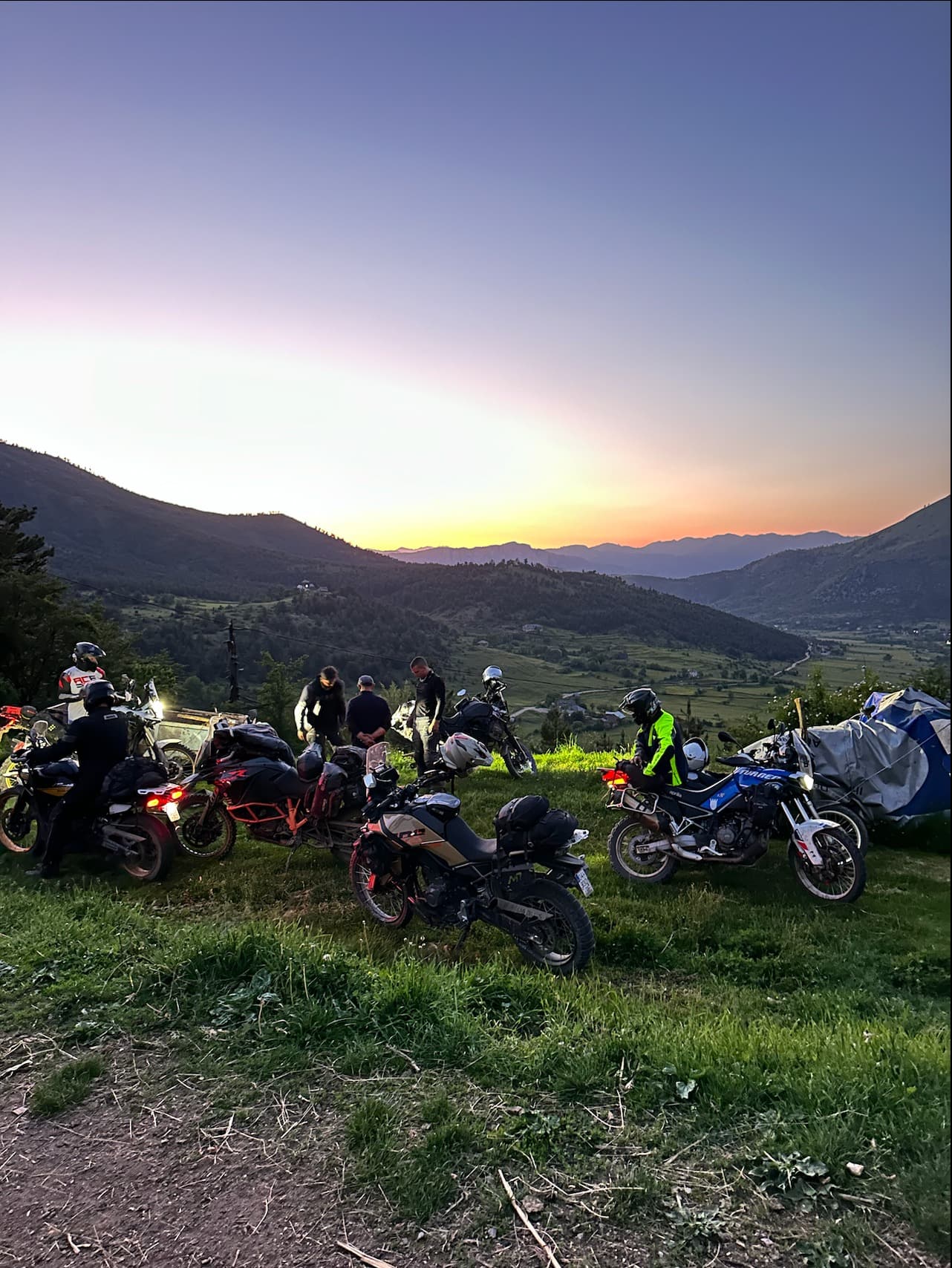 Enduro riders on dusty Kosovo mountain trail at golden hour