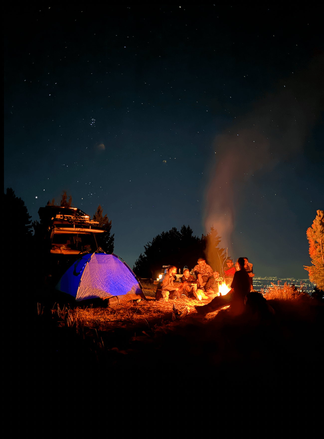 Small group of enduro riders gathered around campfire in Kosovo mountains at night